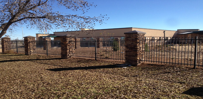 Fence with metal pickets and metal-capped stone pilasters